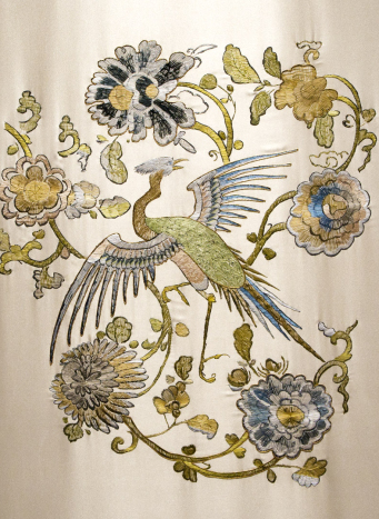 Zbliżenie na fragment haftu. Jest to ptak rajski w otoczeniu kwiatów i wici roślinnych. 