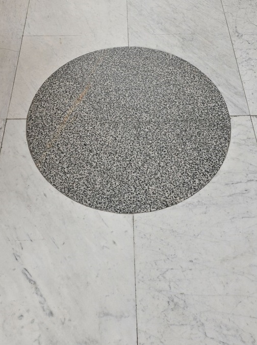 Posadzka z okrągłym, szarym elementem kamiennym. Jest to najcenniejszy fragment posadzki w Lapidarium.