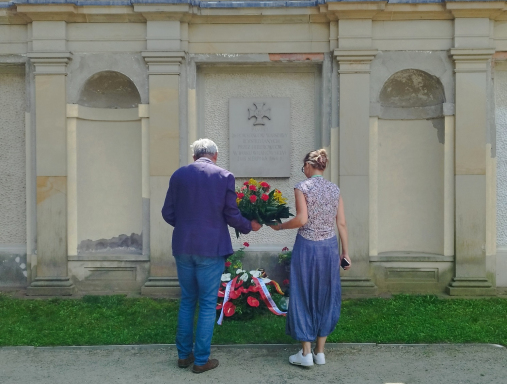 Mężczyzna i kobieta składają wieniec pod pamiątkową tablicą